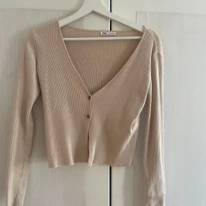 Beige ribbad kofta från Zara - Säljer en beige kofta från Zara med ribbad struktur och v-ringning. Koftan har långa ärmar och knäpps med två knappar fram🫶🏼