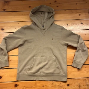 Beige polo Ralph Lauren hoodie  - Säljer en stilren beige hoodie från Ralph Lauren. Den har en klassisk design med en känguruficka framtill och en liten broderad logga på bröstet. Perfekt för en avslappnad look. Hör av dig vid intresse! nypris:1100kr storlek L (14-16)