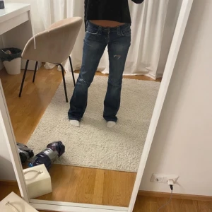 Blå jeans från Lee - Säljer ett par snygga blå jeans från Lee med slitna detaljer på knäna. Passar XS/S