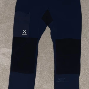 Mörkblå byxor från Haglöfs - Snygga mörkblå byxor från Haglöfs med praktiska dragkedjefickor. Perfekta för utomhusaktiviteter med slitstarka förstärkningar på knäna. Byxorna har en modern passform och är tillverkade i ett hållbart material. Jag har inte använt och helt nya och i  butiker kostar 2199kr 