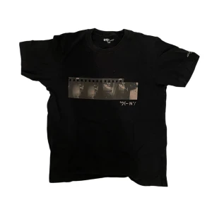 Svart uniqlo t-shirt - Snygg och svart t-shirt från uniqlo med ett unikt filmrulletryck på framsidan. Perfekt för dig som gillar en stilren look med en twist. Kortärmad och bekväm passform.