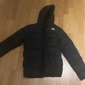 Svart dunjacka från The North Face - Säljer en svart dunjacka från The North Face med huva och dragkedja. Passar alla som är 170-175cm , säljer då den är för liten på mig , annars i bra skick 
