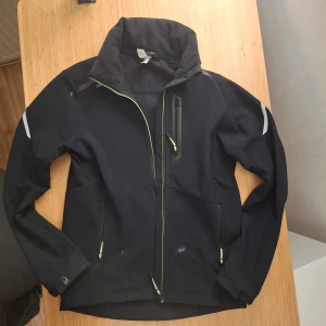Svart vindjacka med dragkedja decathlon  - Säljer en svart vindjacka med dragkedja och reflexdetaljer. flera praktiska fickor med dragkedjor. Perfekt för blåsiga dagar. Lite smuts men kan lätt tvättas bort storlek xs ställ gärna frågor 😊