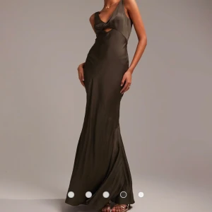 Skogsgrön maxiklänning i satin med snurrad knut framtill (ASOS) - Helt ny och oanvänd klänning från Asos i strl 36. Alla lappar kvar. Säljes då returtiden gått ut.  Nypris 999:-.