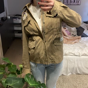 Militär grön jacka från Svea - Säljer en grön jacka från Svea med flera coola patches på ärmarna och bröstet. Jackan har långa ärmar och praktiska fickor framtill. Perfekt för en avslappnad stil. 🧥✨Nypris: 1500kr