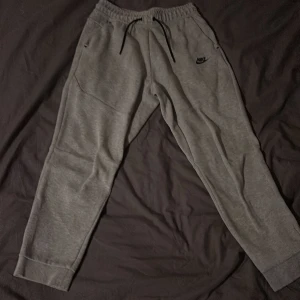 Grå Nike tech byxor - Säljer ett par grå nike tech byxor. Har tyvärr växt ur dom. Pris kan diskuteras☺️