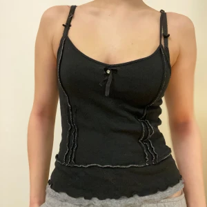 Super söt svart topp med rosett - Snygg svart ribbad linnetopp. Köpt i vintage butik men aldrig använd av mig så den är i bra skick. Den är strechig och kan passa fler storlekar. Hör av dig om du har några frågor :)