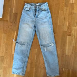 Säljer ett par ljusa jeans med coola slitningar på knäna. De har en hög midja och en straight passform som ger en avslappnad look. Perfekta för en casual outfit!