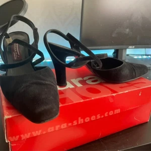 Svarta pumps från Ara - Säljer ett par eleganta svarta pumps från Ara. De har en klassisk design med spetsig tå och en bekväm klack. Skorna är i mocka och passar perfekt för både fest och mer formella tillfällen.