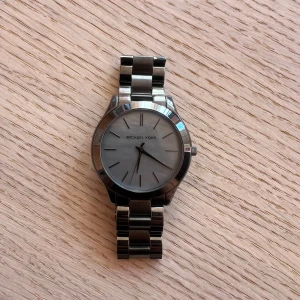 Michael Kors klocka - Säljer en damklocka från Michael Kors i mörkgrått (MK3413). Funkar fint MEN behöver byta batteri då jag inte använt den på länge…  Diameter: Ø 42.00 mm Tjocklek: 8.00 mm Boett: Grå stål Urtavla: Gråmelerad Urverkstyp: Kvarts (batteridrivet)