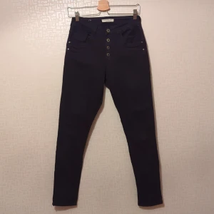 Svarta byxor från Jewelly - Säljer ett par mörkblå byxor från Jewelly i storlek XS/34. De är högmidjade med knappar framtill och har en skinny passform. Sparsamt använda.
