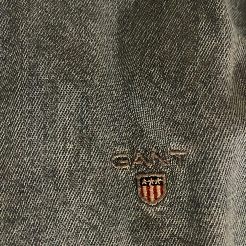 Säljer en snygg blå jeansskjorta från GANT i bra skick. Skjortan har långa ärmar och knappar framtill. Perfekt för både vardag och lite finare tillfällen. Den är tillverkad i ett slitstarkt material och har en broderad logga på bröstet. Passar perfekt för höst och vår!. Paidat.