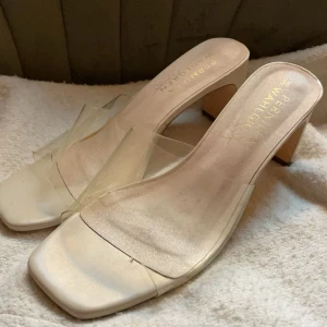 Beige klackskor från Pernilla Wahlgren - Säljer ett par eleganta beige klackskor från Pernilla Wahlgren. De har en stilren design med transparenta detaljer. Klackarna har vissa märken men när man har på sig dem så tänker man inte på det.