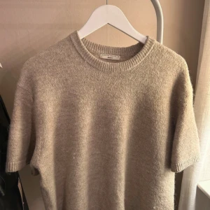 Beige tröja från Gina Tricot - Säljer en stilren beige tröja från Gina Tricot i premiumkvalitet. Tröjan har korta ärmar och en rund halsringning, perfekt för en avslappnad look. Passar bra till både jeans och kjol.