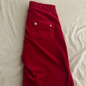 Röda mjukisbyxor från Juicy Couture - Säljer ett par snygga röda mjukisbyxor från Juicy Couture i storlek XS. Har sprättat upp byxorna längst ner på benet i sömmen eftersom dem va för korta för mig, men kom på att dem inte enväldes tillräckligt mycket för att ha kvar endå. Dem är i ganska bra skick, förutom  uppsprättade så är det inga defekter på dem💕 skriv för fler frågor eller bilder 