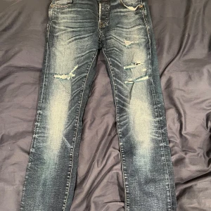 Jeans från Jack & Jones - Snygga jeans från Jack & Jones i en mörkblå tvätt med slitna detaljer. Modellen är slim fit och har en klassisk femficksdesign. Perfekta för en avslappnad stil.