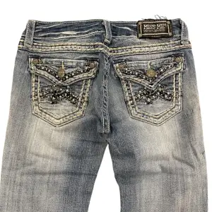 Ett par Low Waist Bootcut Miss Me Jeans i storlek 27. Jeansen är i fint skick med inga skador men några få fläckar men inget jätte tydligt. Mått: Midja: 35 cm tvärs över, ytterbensmått: 101 cm, innerbensmått: 79 cm. Vid fler frågor tveka inte att kontakta oss!