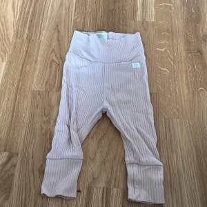 Ribbstickade leggings från H&M - Säljer ett par ribbstickade leggings från H&M i en mjuk rosa nyans. De har en hög midja och är tillverkade i ett bekvämt bomullsmaterial. Perfekta för en avslappnad stil.