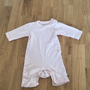 Ljusrosa babybody från Friends - Söt ljusrosa babybody från Friends i mjukt bomullsmaterial. Bodyn har långa ärmar och praktiska knappar i grenen för enkel på- och avklädning. Perfekt för de allra minsta! 💕