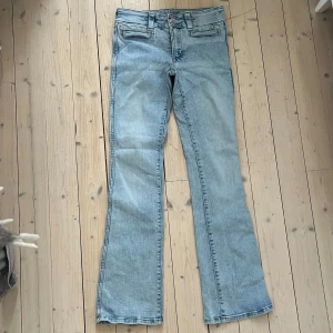 Bootcut jeans från H&M - Säljer ett par ljusblå bootcut jeans från H&M i storlek 170. De har låg midja och justerbar midja för perfekt passform. Skicket är bra och de är superbekväma att ha på sig. Midjemått: 36cm Innerbenslängd: 77cm