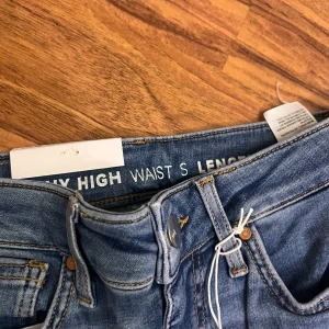 Blå skinny jeans från H&M - Snygga blå skinny jeans från H&M med hög midja. Perfekta för en stilren look. De har klassisk femficksdesign och knappgylf.