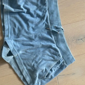 Blå frottéshorts från Juicy Couture - Säljer ett par mjuka och bekväma blå frottéshorts från Juicy Couture. Shortsen har en dragsko i midjan för justerbar passform. Perfekta för en avslappnad dag hemma eller på stranden.