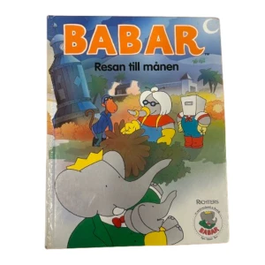 Babar: Resan till månen - En charmig barnbok om Babar, elefanten, och hans äventyr till månen. Omslaget visar Babar i en grön kostym med en gul krona, omgiven av sina vänner i rymddräkter. Perfekt för unga läsare som älskar äventyr och fantasi!