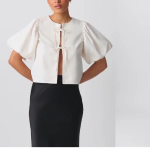 Vit kortärmad blus med knyt - Säljer denna fina vita blusen med korta puffärmar och knyt framtill. Perfekt för både vardag och fest! Blusen har en stilren design med en luftig passform. Köpt från Plick men var dessvärre för stor för mig❣️🤗 skriv för fler bilder🥰