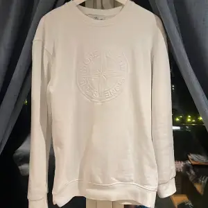 Säljer en stilren vit sweatshirt från Stone Island med ett diskret broderat emblem på bröstet och det klassiska märket på ärmen.    Köpte tröjan för 2700kr nästan aldrig andvänd som ny. Tröjan är i storlek xl men är jätte liten är storleken jag är 177 och har storlek s och den passar mig perfekt så mellan s och xl 