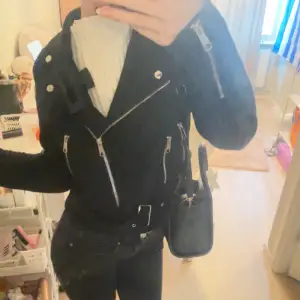 Säljer en snygg svart skinnjacka med coola dragkedjedetaljer. Jackan har en tight passform och är perfekt för höst och vår. Den har långa ärmar och en klassisk bikerstil. Perfekt för att ge din outfit en edgy touch!