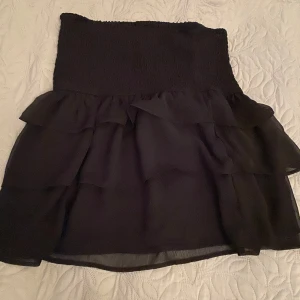 Svart volangkjol - Säljer en superfin svart kortkjol med volanger. Perfekt för fest eller en utekväll! Den har en elastisk midja som gör den bekväm och lätt att bära. Kjolen är i nyskick och passar perfekt till både sommar och höst. 🖤