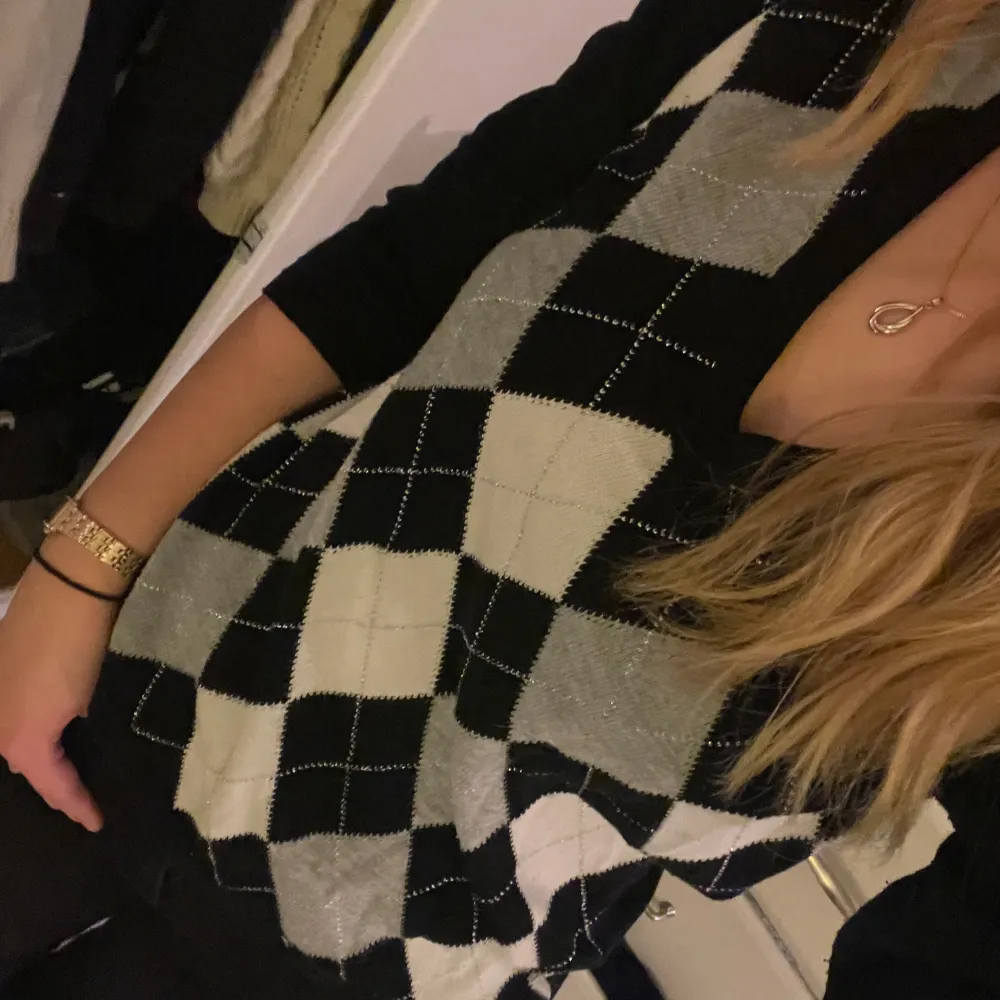 Säljer en snygg svart och vit rutig tröja med v-ringning. Den har långa ärmar och ett klassiskt argyle-mönster som ger en stilren look. Passar bra till jeans eller kjol! Köpt second hand och är väl använd men har inga defekter.. Tröjor & Koftor.