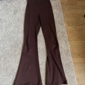 Bruna ribbade yogapants  - Säljer ett par snygga bruna ribbade byxor i storlek S. De är högmidjade och har en bootcut-stil som ger en trendig look. Perfekta för både vardag och fest! 👜✨