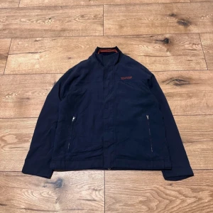 Mörkblå jacka från Polo Jeans Co. - Säljer en snygg mörkblå jacka från Polo Jeans Co. Ralph Lauren. Den har en stilren design med dragkedja och knappar framtill. Perfekt för höst och vår med sin lätta men skyddande stil. Jackan har långa ärmar och två praktiska fickor med dragkedja. Passar både till vardags och lite finare tillfällen.