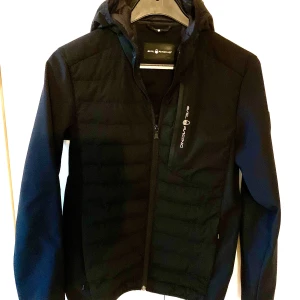 Sail Racing Antarctica Hybrid Hood  - SAIL ANTARCTICA EXPEDITION   Jackan är i mycket fint skick !  Dock finns ett litet märke på baksidan av vänster ärm. (efter en vurpa i gympasalen) se sista bilden.