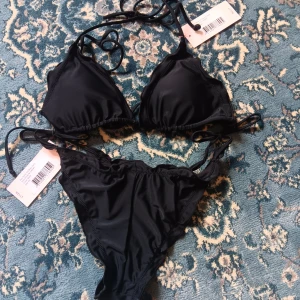 Svart bikini med knytband - Snygg svart bikini i nyskick (oanvänd) med knytband. Köpt från Nelly!