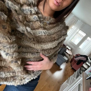 Brun pälsponcho - Säljer en supermysig brun poncho i äkta päls. Den har en loose passform och är enkel att slänga över vilken outfit som helst.