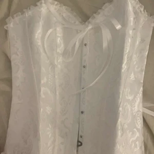 Vit korsett med spetsdetaljer - Säljer en superfin vit korsett med spetsdetaljer och snörning i ryggen. Perfekt för fest eller halloween tillfällen! 💖 Skickar direkt!