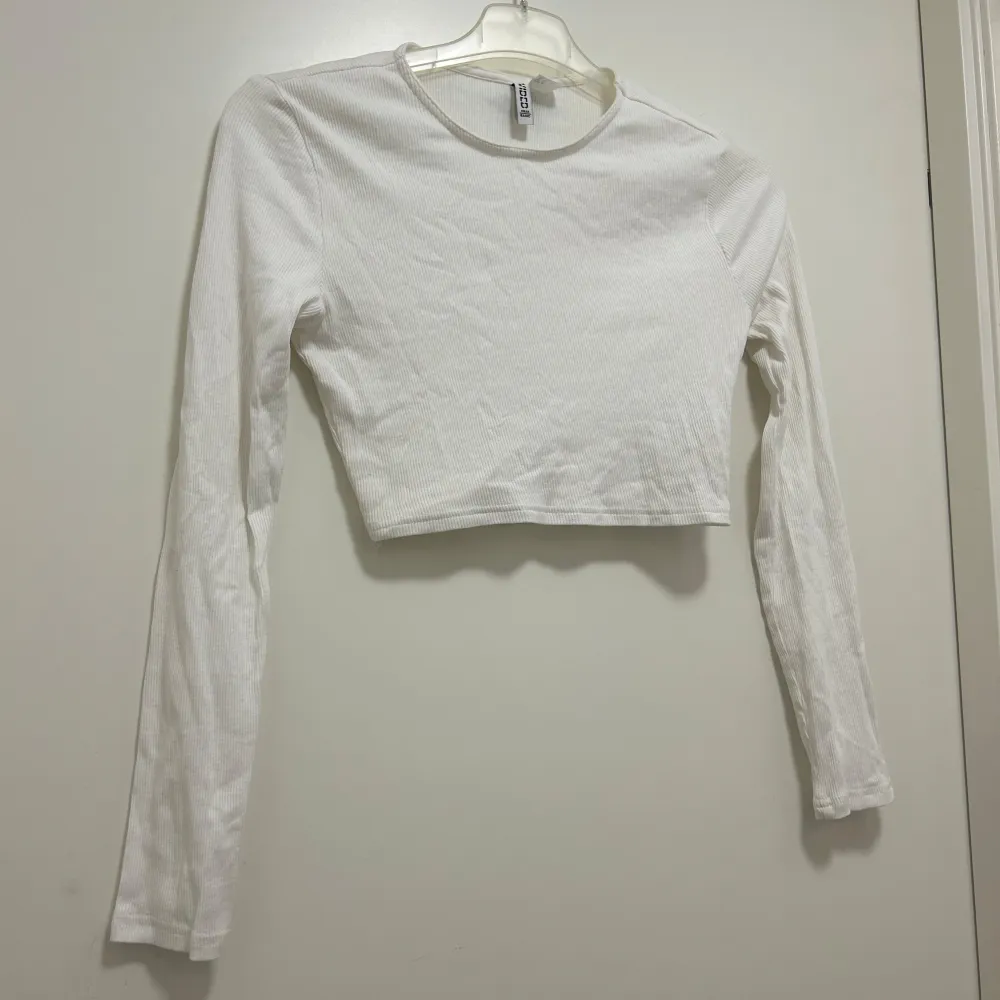 En vit, långärmad croptop som är tunt ribbad. Tröjan i sig är mycket skön men är för kort för min smak. Passar bra till allt!. T-shirts.