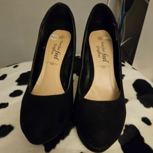 Mocka klackskor nyskick  - Mocka Säljer ett par svarta klackskor från märket Your Feet Feel Gorgeous. Skorna är i ny skick, lite smutsig på sulan. De har en hög klack och är perfekta för festliga tillfällen. Innemått ca 25 cm . Klack 10 cm