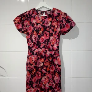 Blommig klänning från Bik Bok - Säljer en superfin blommig klänning från Bik Bok i storlek S. Den har en härlig mix av rosa och röda blommor på en svart bakgrund. Klänningen är kortärmad och har en öppen rygg som ger en extra touch. Perfekt för sommarens fester eller en mysig vårdag! Den är oanvänd och helt ny!!