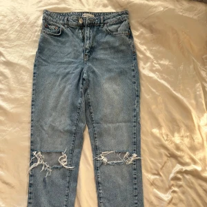 Blå jeans med slitna knän  - Säljer ett par snygga blå jeans i storlek 36 som har en slitning vid knäna. De är super bekväma och i bra skick