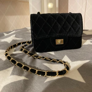 Väska mini sammet - Söt liten väska i sammet med ett rutigt mönster. Väskan har ett litet axelband (110 cm långt) och ett lås i guldfärgade detaljer. 