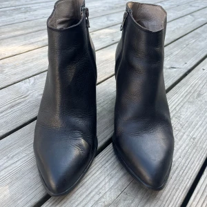Svarta stövletter med klack - Säljer ett par snygga svarta stövletter från Filippa K i skinn med spetsig tå och dragkedja på sidan. De har en bekväm klack som ger lite extra höjd utan att kompromissa med komforten. Perfekta för både vardag och fest! Använda mycket sparsamt.