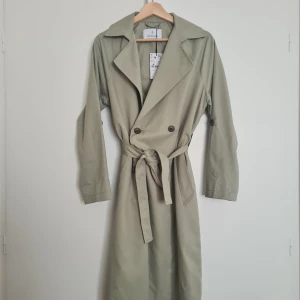 Stradivarius – trenchcoat - Superfina trenchcoat från Stradivarius i en ljusgrön färg 💚 Perfekt som höst eller vårjacka då den är lite tunnare i tyget. Den är lite oversized men passar bra då man kan knyta i midjan. Aldrig använd bara testad!
