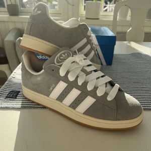 Adidas Campus 00’s Sneakers Light Grey  - Helt nya och oanvända Adidas Campus 00’s Sneakers i ljusgrå färg. Storlek 48 men passar mindre=46,5/47. Box, extra snören medkommer. Orderbekräftelse finns. Perfekt skick. Populära & trendiga. Nypris 1500kr. Pris kan diskuteras. Hör av dig i DM! 