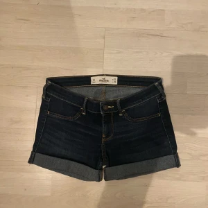 Mörkblå jeansshorts från Hollister - Snygga mörkblå jeansshorts från Hollister med uppvikta kanter.De har en knapp och dragkedja framtill. Midja 26, storlek s 