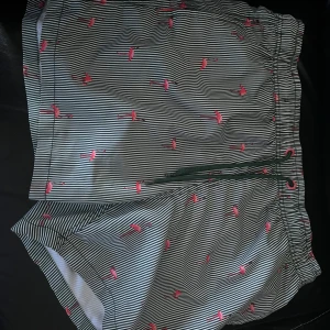 Randiga badshorts med flamingomönster från Esprit - Snygga badshorts från Esprit med ett coolt randigt mönster i svart och vitt, dekorerade med rosa flamingos. De har en elastisk midja med snörning för perfekt passform. Perfekta för en dag på stranden eller vid poolen!