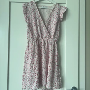 Annika teller x NAKD klänning - Söt blommig klänning från NAKD X Annika Teller. Den har en v-ringad design med volangdetaljer på ärmarna och ett elastiskt band i midjan för en bekväm passform. Knappt använd och normal i storlek