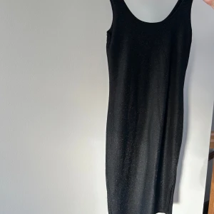 Svart glittrig klänning från Bik Bok - Snygg svart klänning från Bik Bok med glittrande detaljer. Den är ärmlös och har en slits på sidan som ger en extra touch. Perfekt för sommaren och fest! ✨